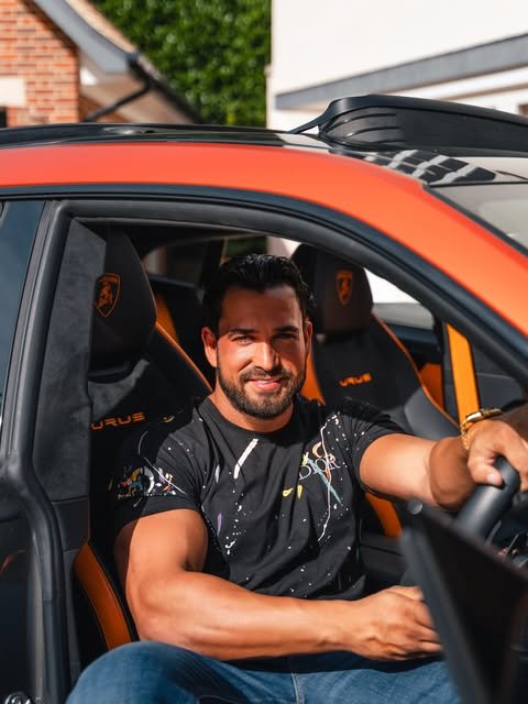 Addam Sattar in the driver's seat of an orange Lamborghini Urus
