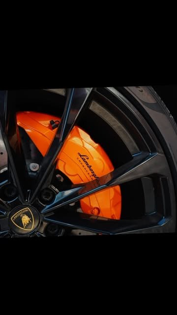 Orange Lamborghini brake caliper behind a black wheel